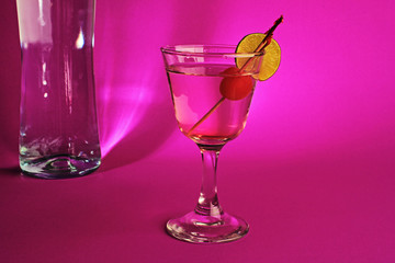 Happy Hour Cocktail and bottle of Gin in harsh purple light of Night Life