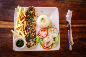 beef filet cooked Argentinean style and served on a plate with accompaniment on a rustic wooden...