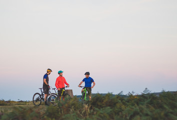 Mountain Bike Riding Friends on Hill at Sunset