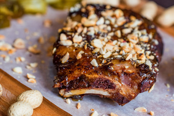Close up board with pork ribs grilled with BBQ sauce and peanuts