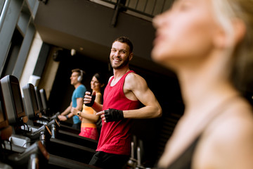 young people running on treadmills in modern gym