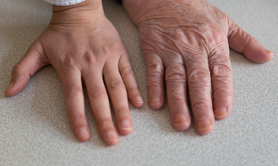 old woman wrinkled and young hands on the background.