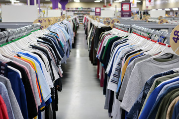 Knitted T-shirts hanging in two rows on hangers in the store blurred. On the eve of Black Friday. Background for design from a department store.