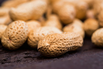 Close up pile of unpeeled peanuts on dark wooden background