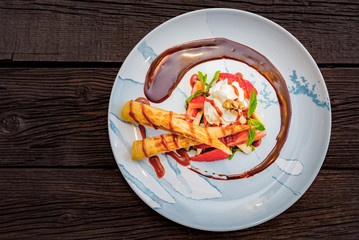 Top view delicious dessert with waffle rolls, ice cream and strawberries