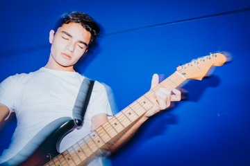 young man with electric guitar on blue background