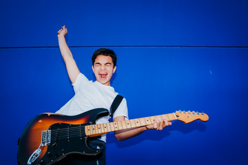 young man with electric guitar on blue background