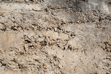 Rough textured concrete wall with protruding rubble for a background or texture.