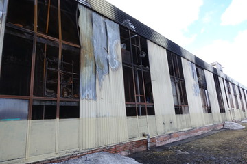 Fototapeta na wymiar Multi-storey parking after a fire. Copy-darkened windows with burned out cars inside