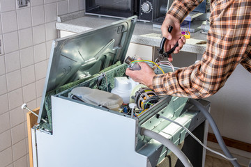 People in technician jobs. Appliance repair technician or handyman works on broken dishwasher in a...