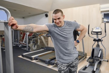 Fototapeta na wymiar Portrait of young smiling strong muscular man in the gym