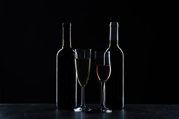 Bottles of wine and different glasses of wine on a dark background