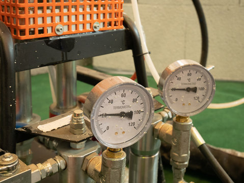 closeup of two analog indicators of temperature with arrows showing current hot or cold condition of liquid paint in automatic pneumatic air pressure equipment, selective focus on closer one - Powered by Adobe
