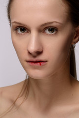 portrait of a young beautiful girl with blood on her lips, on a white background.