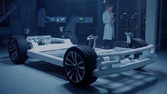 Team of Automotive Engineers / Scientists Discussing, Designing and Working on Electric Car Chassis Prototype. Using 3D CAD Software.Innovative Facility: Vehicle Platform with Wheels, Engine, Battery