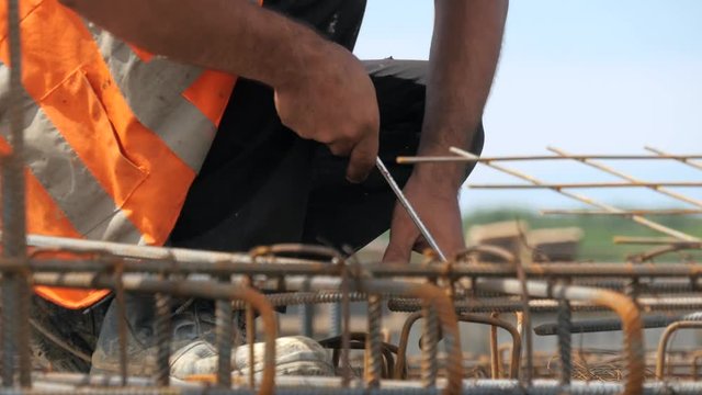 Closeup of a construction worker installing steel rebar on a outdoors industrial site