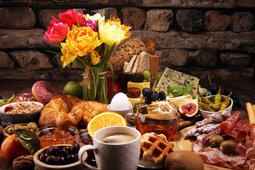 breakfast on table with bread buns, croissants, coffe and eggs