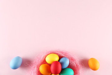 Different Easter eggs in straw nest, beautiful flat lay pastel colored composition on pale gradient paper background. Top view, copy space.