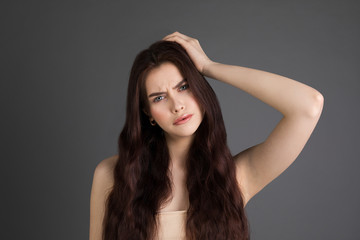 Naklejka premium Portrait of displeased young brunette girl touching hair