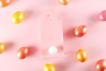 Fototapeta na wymiar Golden and rose gold Easter eggs in beautiful flat lay pastel colored composition on pale pink paper background. Top view, copy space.