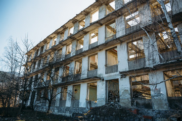 Fototapeta na wymiar Not finished abandoned ruined European building, empty windows and concrete walls