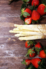 White and green asparagus with strawberries on wood