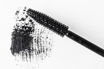 Close-up black mascara brush and brush stroke on white background. The photo is suitable as a background for the theme of decorative cosmetics, beauty, makeup products.