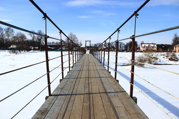suspension bridge over snow-covered river