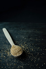 Wheat groats in a wooden spoon on a wooden dark background. Wooden spoon with wheat grains.