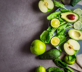 Slice and whole avocado, green apples, lime and spinach on a gray background with free space for the text. Square format. top view