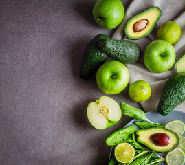 Slice and whole avocado, green apples, lime and spinach on a gray background with free space for the text. Square format. top view