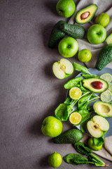 Slice and whole avocado, green apples, lime and spinach on a gray background with free space for the text. top view