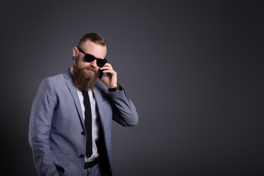 Geschäftsmann mit Bart telefoniert mit Handy zeigt Finger Sonnenbrille