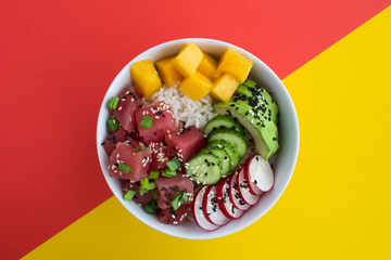 Poke bowl with tuna in the white bowl in the center of the colorful background.Top view.Closeup.