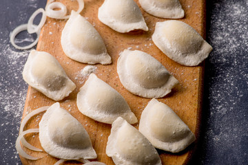 frozen khinkali and dumplings on a dark background with ingredients and spices. Semi-finished products