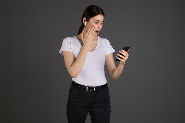 Studio portrait of shoked and confused woman receiving concerning and troublesome message via smartphone open mouth