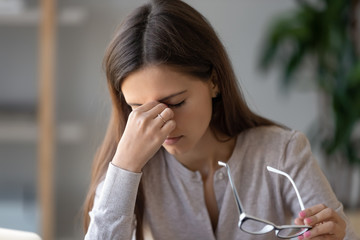 Close up portrait woman taking off eyeglasses suffers eye strain