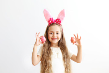 Obraz na płótnie Canvas Portrait of cute little five year old girl with long blond hair wearing easter bunny ears with pink polka dot bow, smiling and having fun on holy day. Isolated white backgroung, copy space, close up.