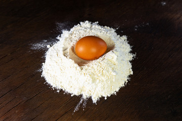 brown egg in white flour on wooden background