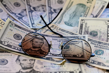Sunglasses is placed on the banknote of US dollars spread around