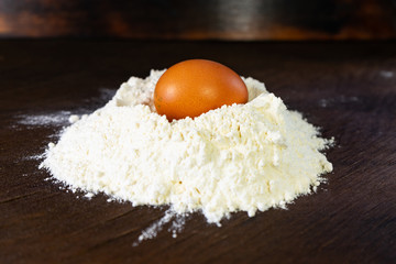 brown egg in white flour on wooden background