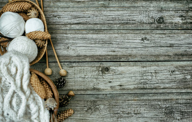 White wool threads roll inside basket with knitting and knitting needles on vintage wood