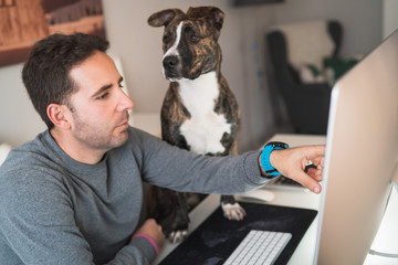 Freelancer man working from home with his dog sitting together in the office