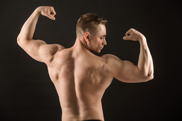 Fototapeta na wymiar handsome muscular man on black background showing biceps