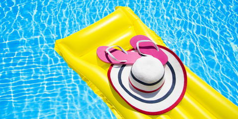 Beach summer holiday background. Inflatable air mattress, flip flops and hat on swimming pool....