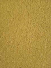 Texture of stone wall painted with yellow stucco