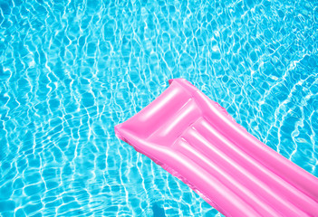 Beach summer holiday background. Inflatable air mattress on swimming pool water. Pink lilo and summertime accessories on poolside. Top view and copy space