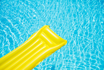 Beach summer holiday background. Inflatable air mattress on swimming pool water. Yellow lilo and summertime accessories on poolside. Top view and copy space. Banner - obrazy, fototapety, plakaty