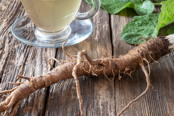Burdock roots on a table, with tea in the background