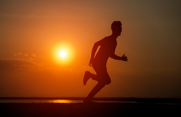 Silhouette of the running boy at sunrise.